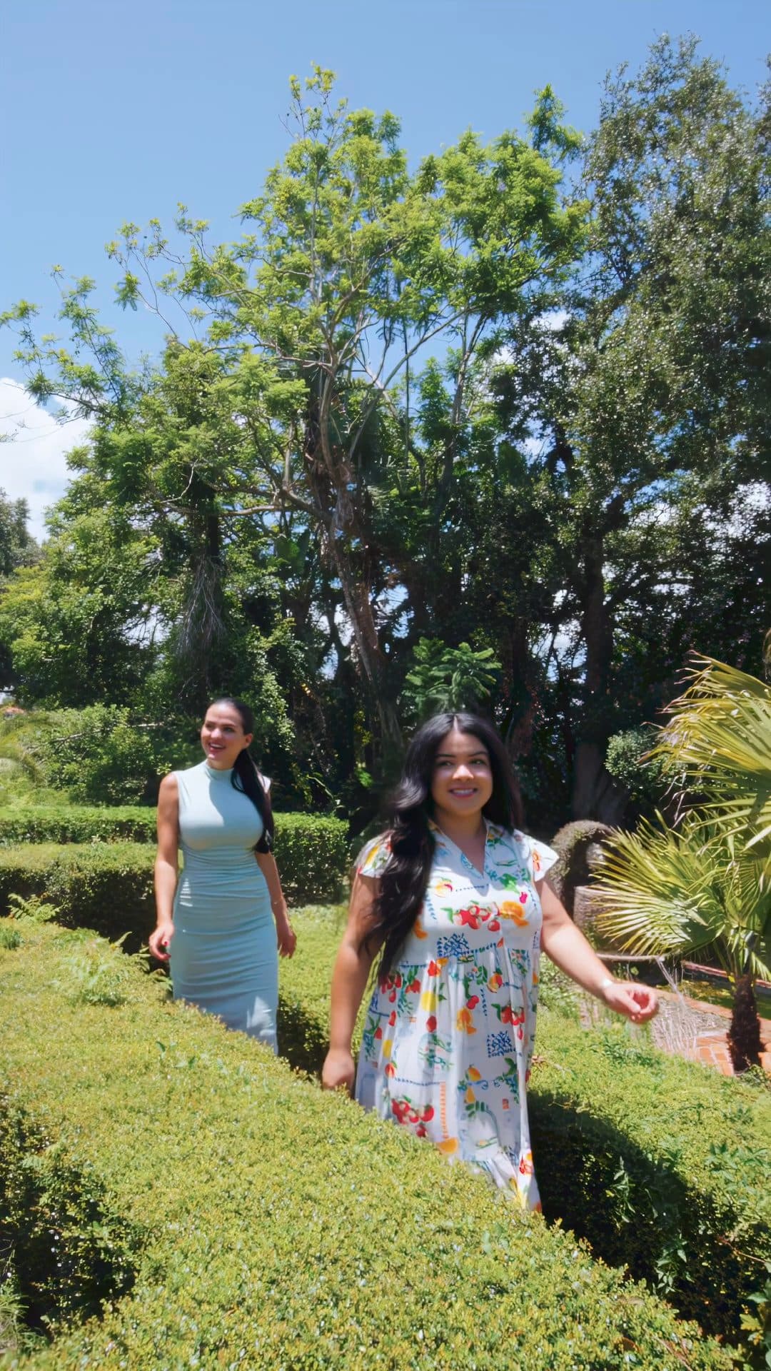Luana and Nelly walk through the hedge garden at 1121 Sunset Dr, a still from the video tour