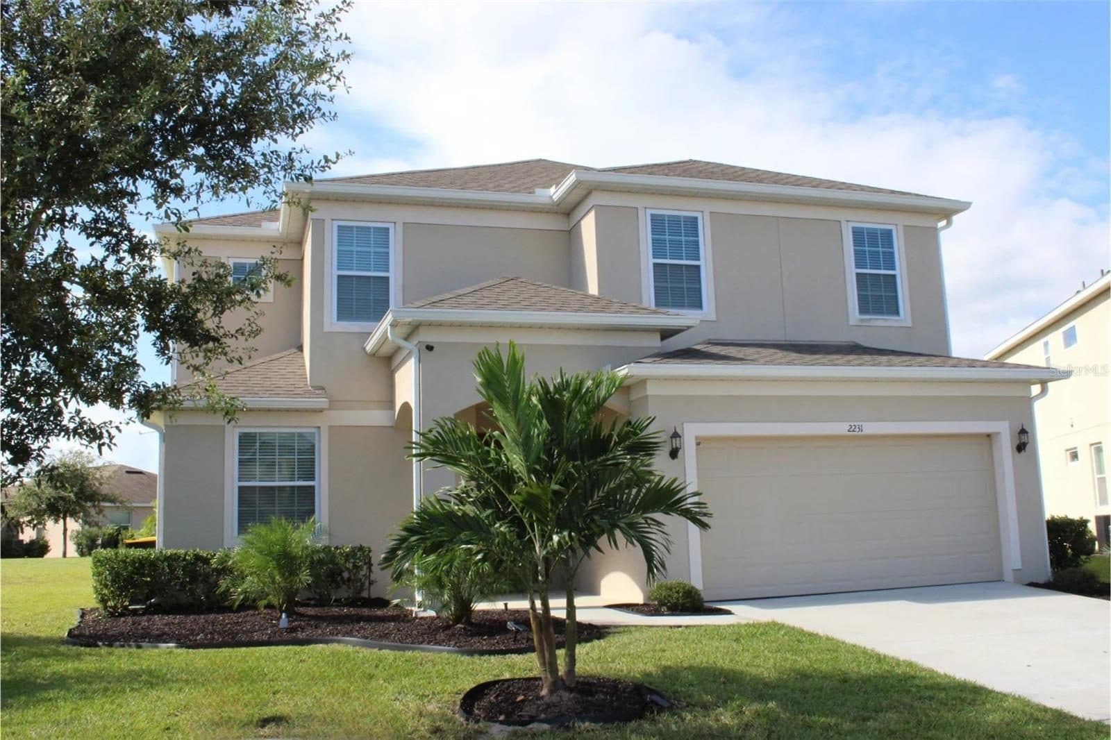 Front of 2231 Crofton Springs Ct, a two-story home with a two-car garage, an arched entry, and a palm tree in the front bed