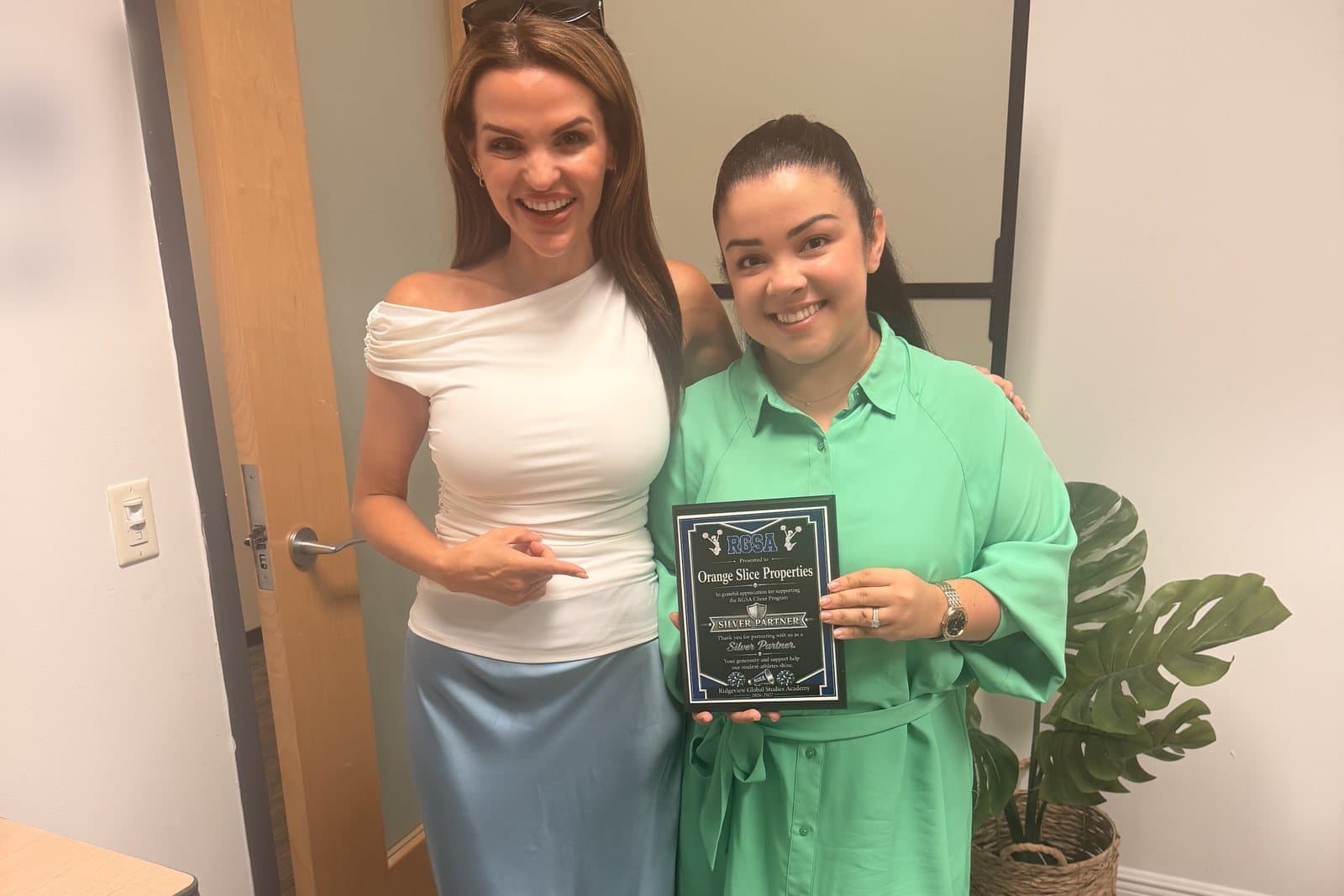 Luana and Nelly holding the Silver Partner plaque from the Ridgeview Global Studies Academy cheer program