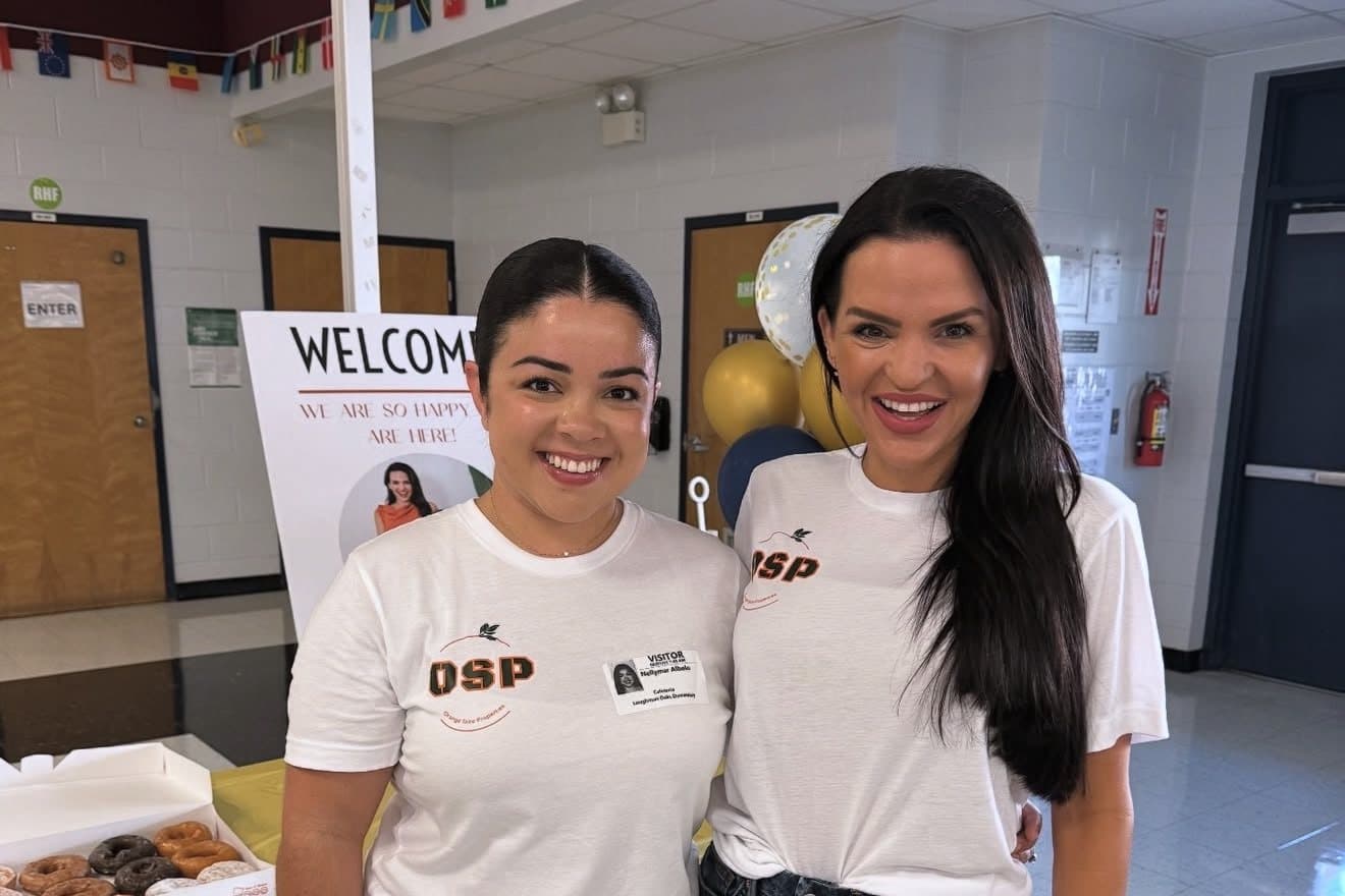 Luana and Nelly in matching Orange Slice T-shirts at a school welcome table