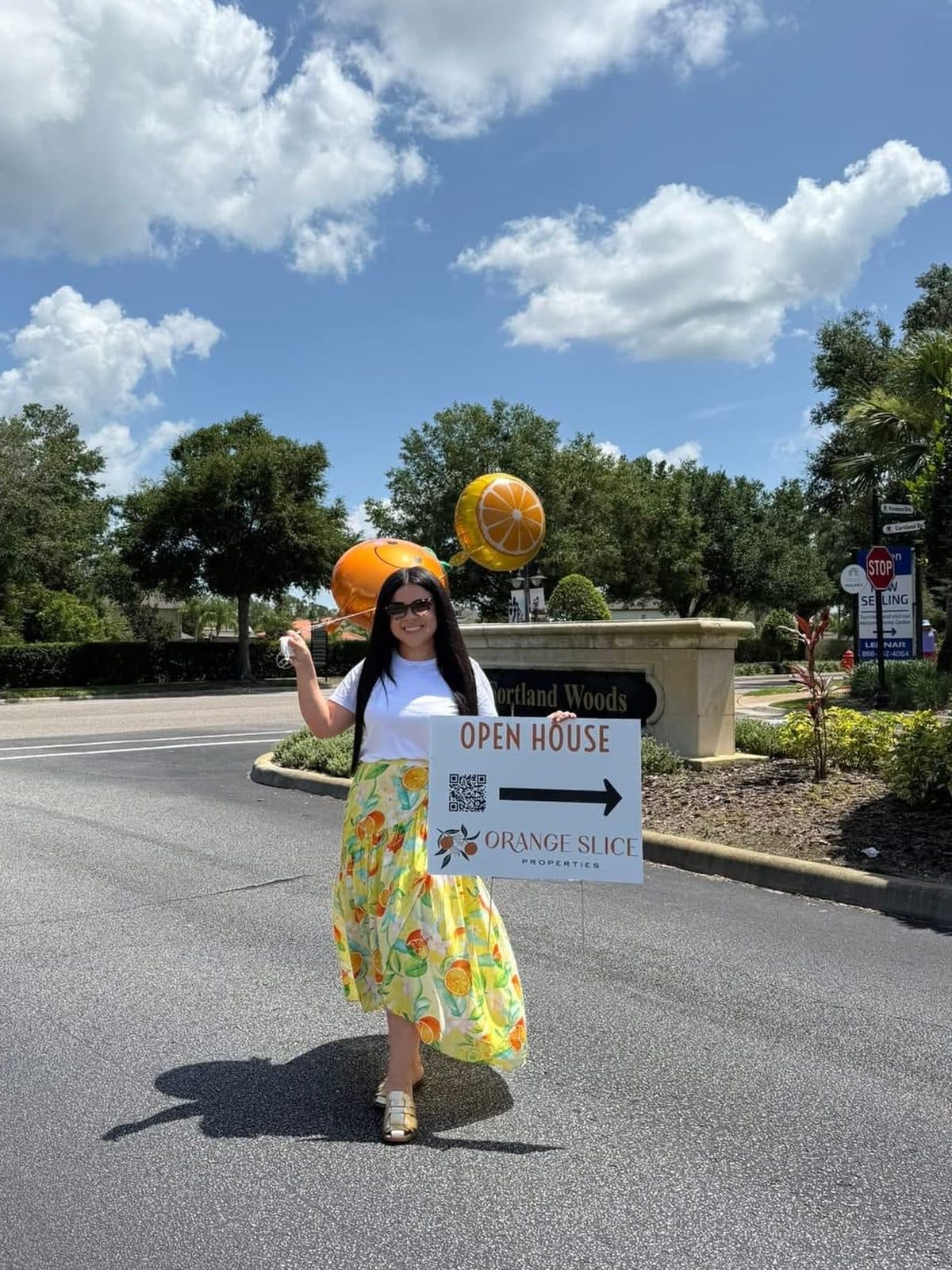 Nelly at the Cortland Woods entrance in Providence with orange balloons and an Orange Slice "Open House" sign pointing the way