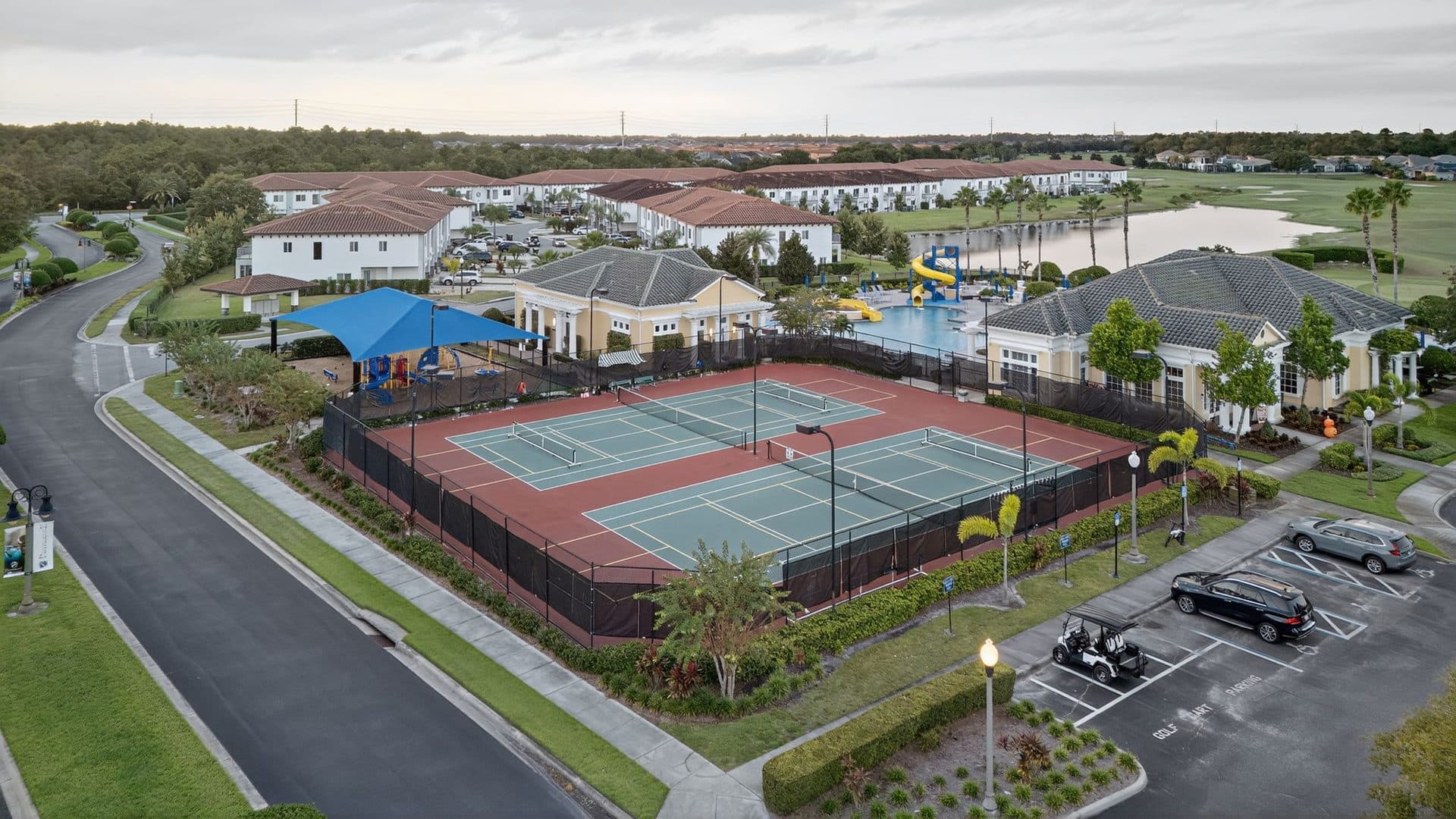 Aerial view of the Providence tennis courts beside the community pool, with a shaded playground